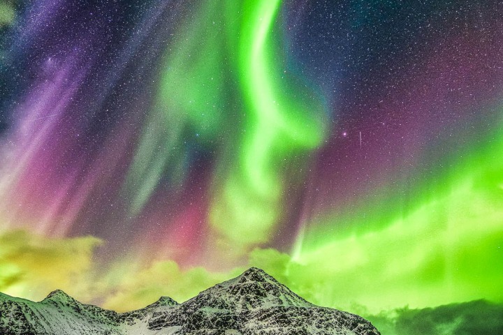 Aurora Borealis (Northern lights) explosion over mountains and rural road